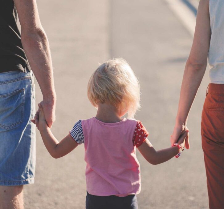 הורים הולכים יד ביד עם ילדה