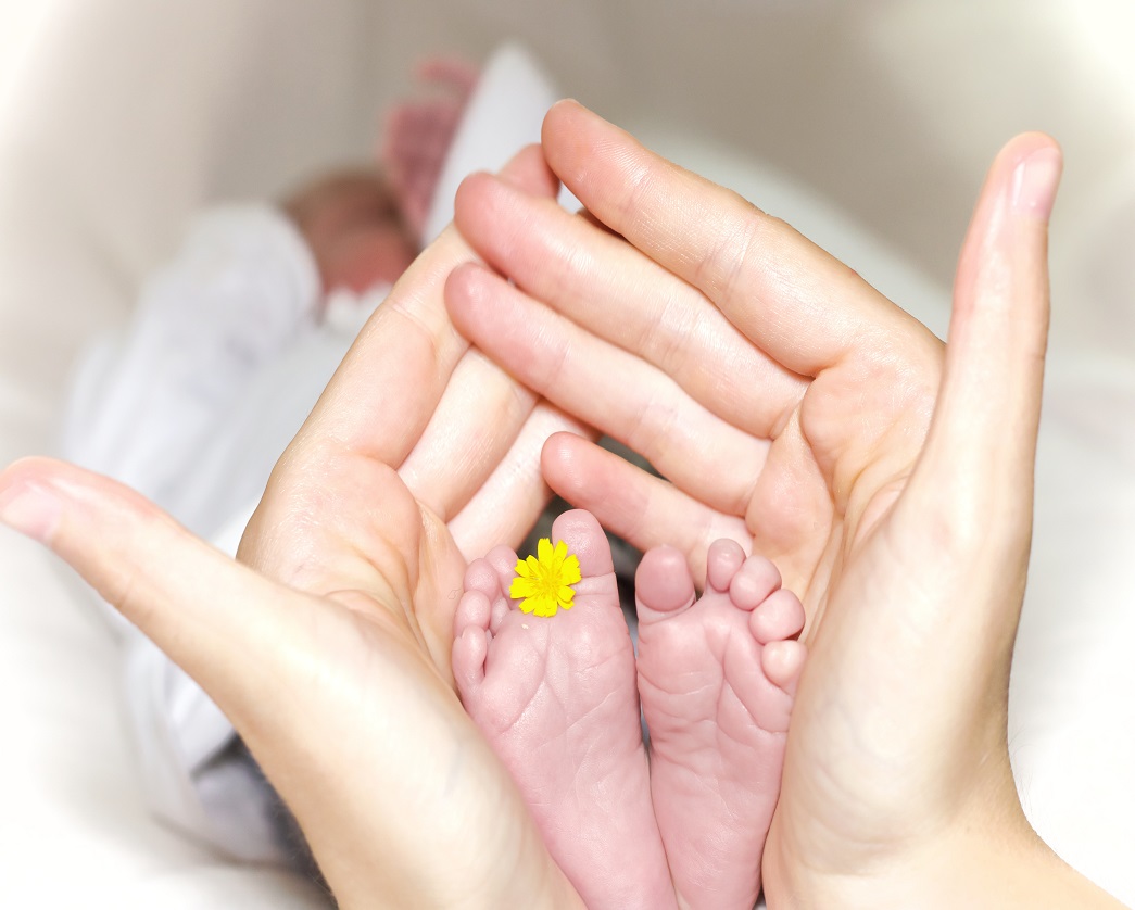 ידיים אוחזות ברכות ברגלי תינוק