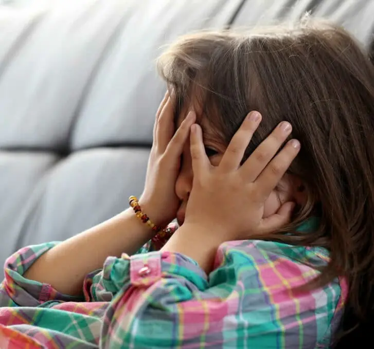 ילד קטן מסתיר את עיניו על ספה